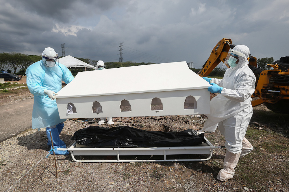 Workers wearing personal protective equipment (PPE) carry the body of a Covid-19 victim at a cemetery in Shah Alam February 11, 2021. u00e2u20acu201d Picture by Yusof Mat Isa