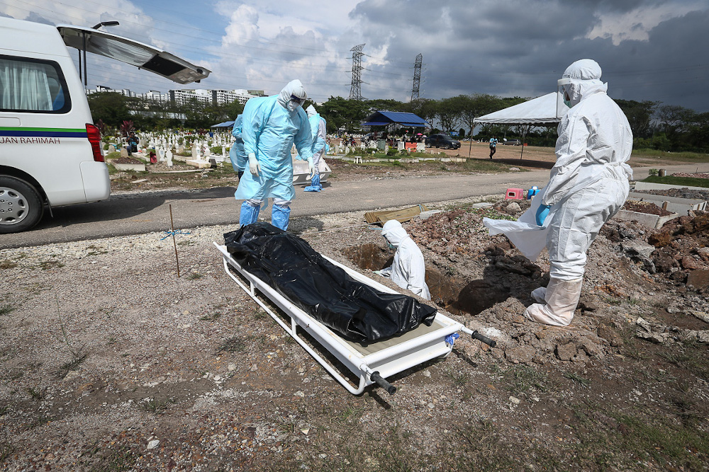 Workers wearing personal protective equipment (PPE) bury the body of a Covid-19 victim at a cemetery in Shah Alam February 11, 2021. u00e2u20acu201d Picture by Yusof Mat Isa
