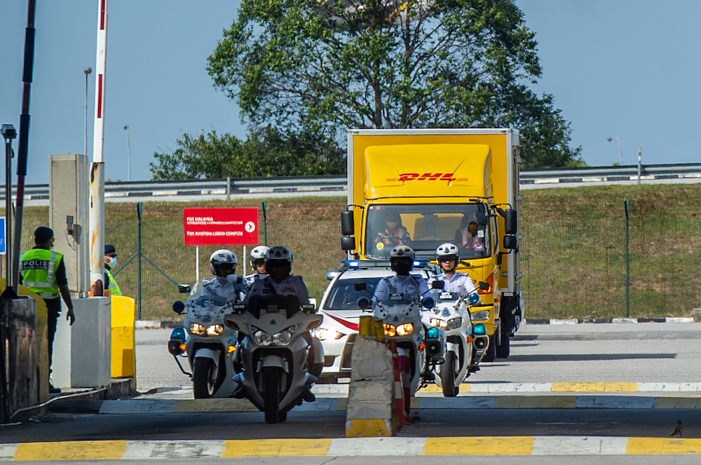 A convoy of DHL Express vehicles carry the first batch of Pfizer-BioNTech's Covid-19 vaccine with police escort from Cargo Village in KLIA, February 21, 2021. u00e2u20acu201d Picture by Shafwan Zaidon