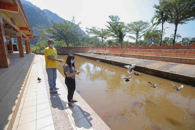 Perak Kwan Yin Tong Temple committee chairman Ho You Meng and committee member Foo Sze Mei feed fish at Sungai Rapat in front of the temple that hosts thousands who converge there on Chap Goh Meh. u00e2u20acu201d Picture by Farhan Najib
