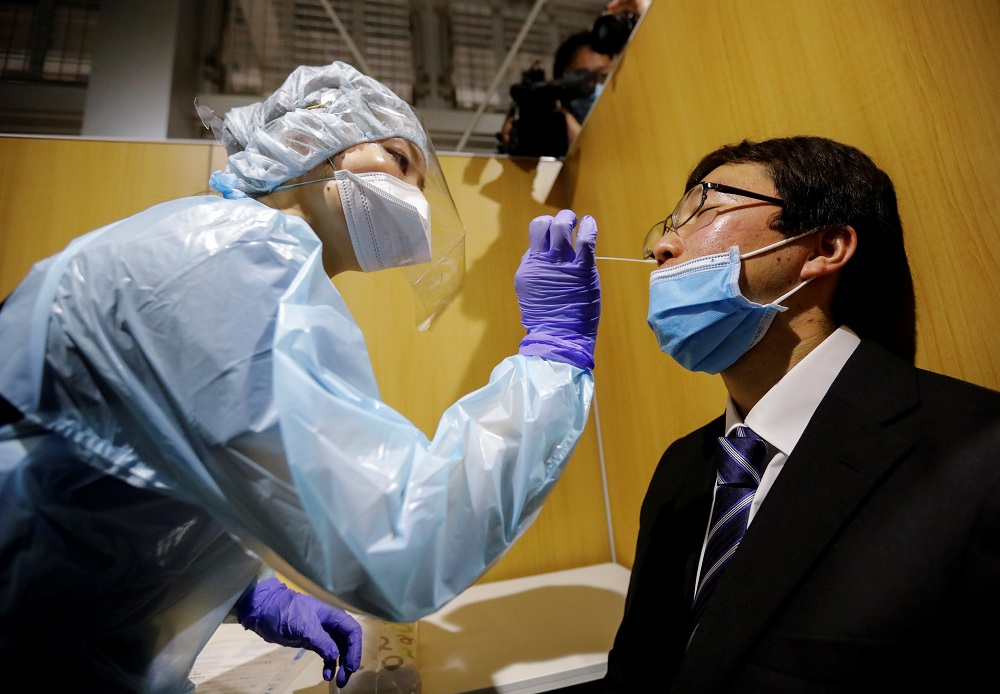 A medical worker wearing a protective suit conducts a simulation for a polymerase chain reaction (PCR) test at the newly opened Narita International Airport PCR Center in Narita, east of Tokyo, Japan November 2, 2020. u00e2u20acu2022 Reuters file pic