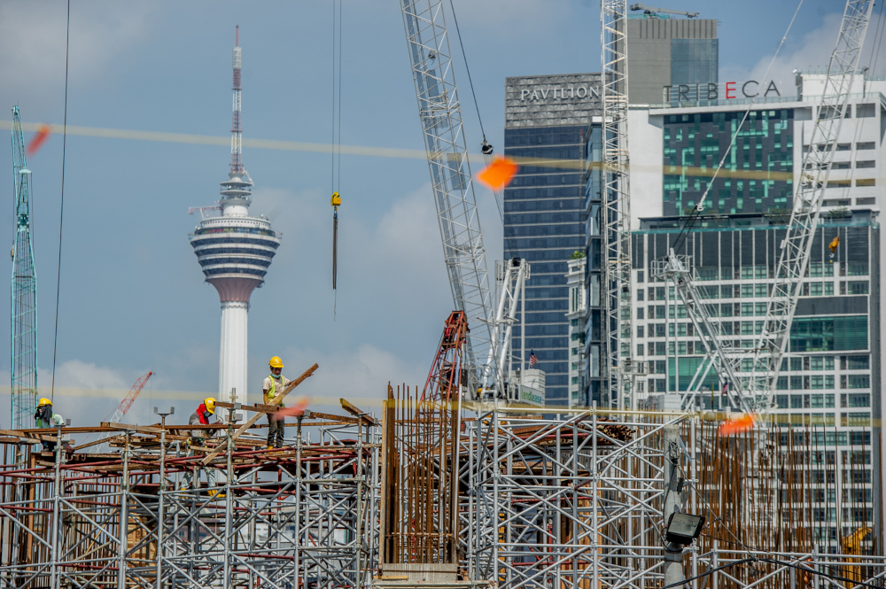 Construction workers walking across a platform at a building site in Kuala Lumpur February 14, 2021. u00e2u20acu201d Picture by Shafwan Zaidon