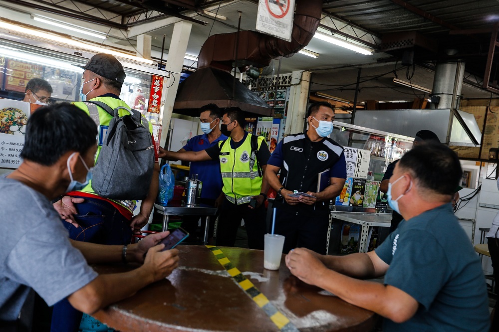 Police officers checking customersu00e2u20acu2122 MySejahtera app during an operation here at a restaurant in Jalan Raja Uda February 17, 2021. u00e2u20acu2022 Picture by Sayuti Zainudin