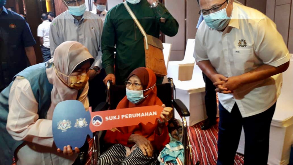 Datuk Zuraida Kamaruddin hands over a replica key to a recipient during the Taman Seri Molek Persana Phase 1 and PPR Taman Perling housing ceremony in Johor Baru February 19, 2021. u00e2u20acu201d Picture by Ben Tan