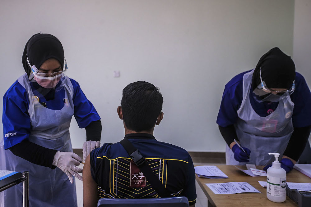 A healthcare worker administers a dose of the Pfizer-BioNTech Covid-19 vaccine to a frontliner at the UiTM Private Specialist Centre in Sungai Buloh March 2, 2021. u00e2u20acu2022 Picture by Hari Anggara