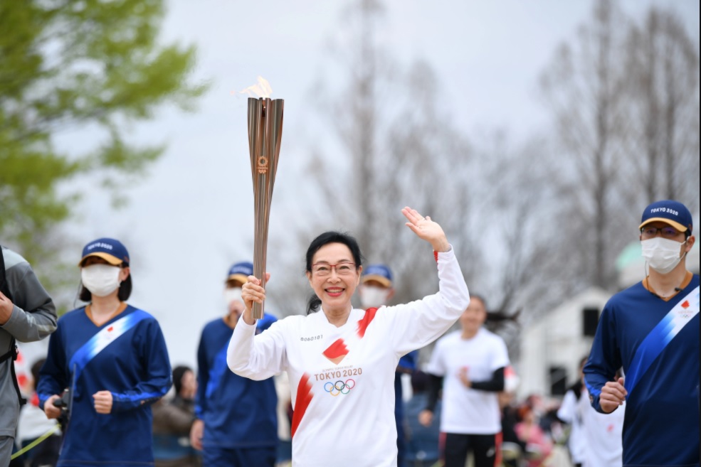 群马县第一位火炬手见城美枝子，正在樱花树下开跑。-摘自东京奥运会官网-