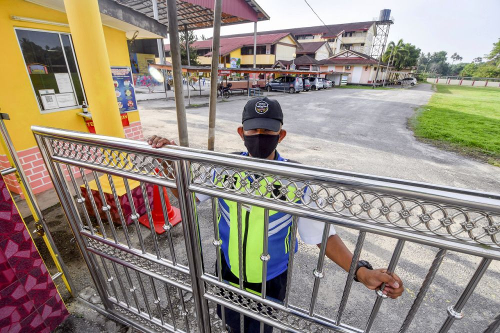 A security guard at Sekolah Kebangsaan Pasir Hor closes the school gate in Kota Bharu April 18, 2021. u00e2u20acu201d Bernama pic