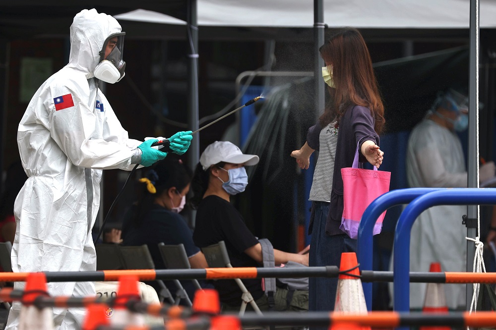 A soldier disinfects a person who is leaving a Covid-19 testing site following a surge of coronavirus disease infections in Taipei May 19, 2021. u00e2u20acu201d Reuters pic