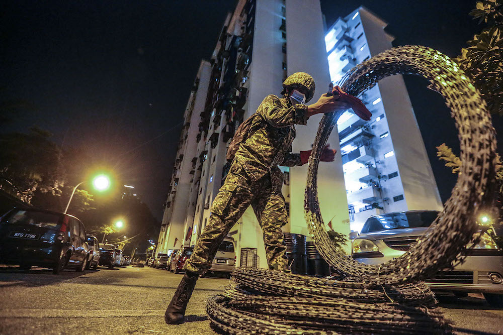Members of the Malaysian Armed Forces (ATM) are seen installing barbed wire around at Kampung Limau People's Housing Project (PPR) area in Kuala Lumpur following the enhanced movement control order (EMCO) from May 23 to June 5. u00e2u20acu201d Picture by Hari Anggara
