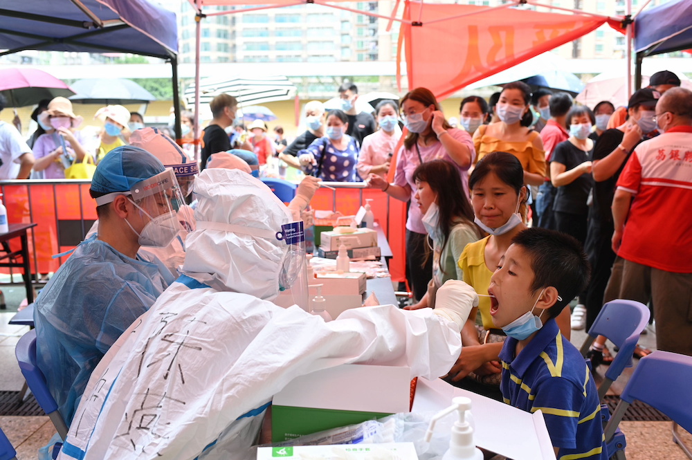 A medical worker collects a swab from a resident during a mass testing for Covid-19 at a makeshift testing site at a stadium in Guangzhou, China May 30, 2021. u00e2u20acu201d cnsphoto via Reuters