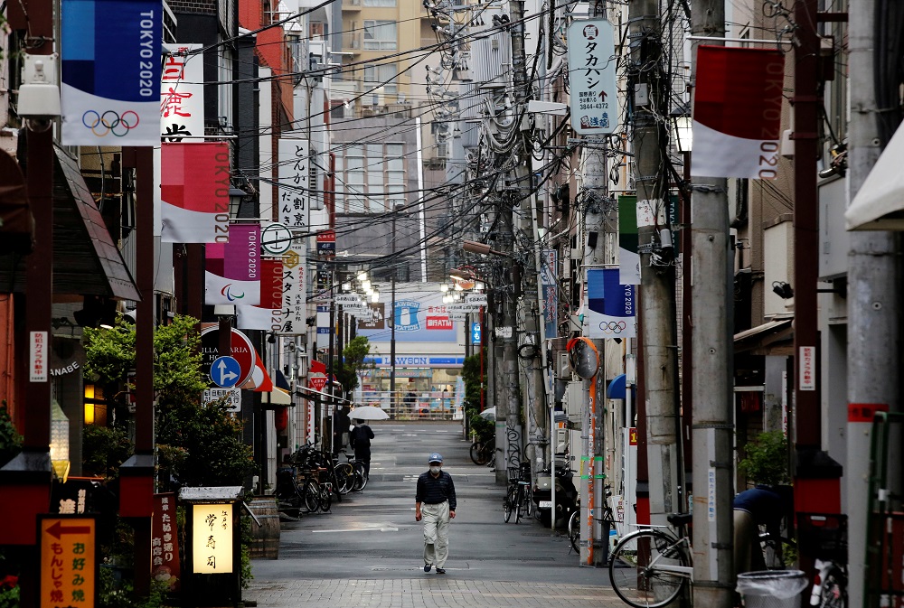 A man wearing a protective face mask walks in a local shopping street decorated with Tokyo 2020 Olympic Games flags, in Tokyo, Japan May 7, 2021. u00e2u20acu2022 Reuters pic