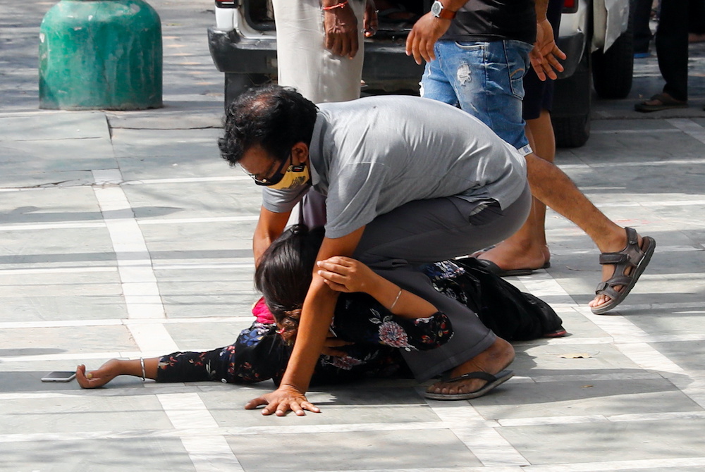 A man tries to lift a woman who fainted after seeing the body of a relative who died from the coronavirus disease, at a crematorium in New Delhi, India, April 30, 2021. u00e2u20acu201d Reuters picnn