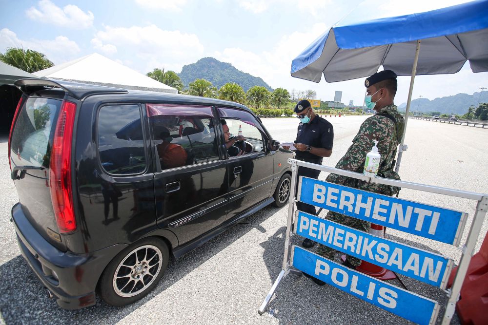Police personnel conduct checks on vehicles at a roadblock during MCO 3.0 at the Ipoh Selatan Toll May 10, 2021. u00e2u20acu201d Picture by Farhan Najib