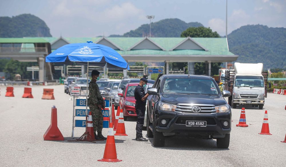 Police personnel conduct checks on vehicles at a roadblock during MCO 3.0 at the Ipoh Selatan Toll May 10, 2021. u00e2u20acu201d Picture by Farhan Najib