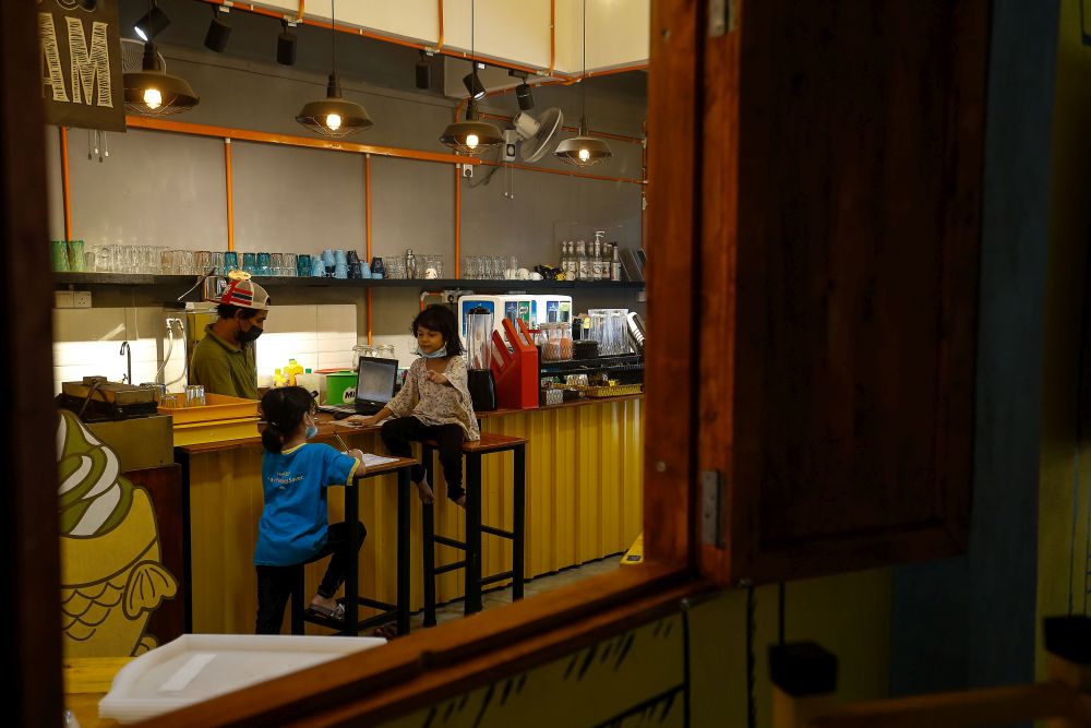 Shamsul Munir Safini's twin daughters Alya and Ayra focus on their homework while he runs his restaurant in Hala Kalui, Seberang Jaya May 17, 2021. u00e2u20acu201d Picture by Sayuti Zainudin