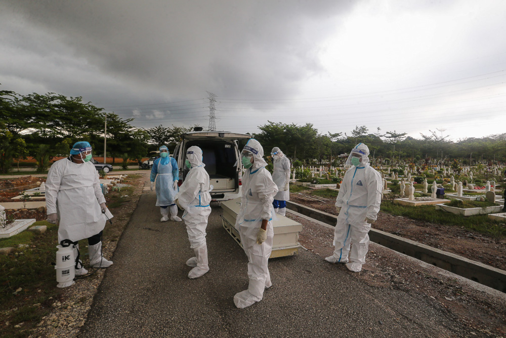 Workers and family members wearing protective suits prepare to bury a victim of the Covid-19 disease at a cemetery in Shah Alam May 18, 2021. u00e2u20acu201d Picture by Yusof Mat Isa