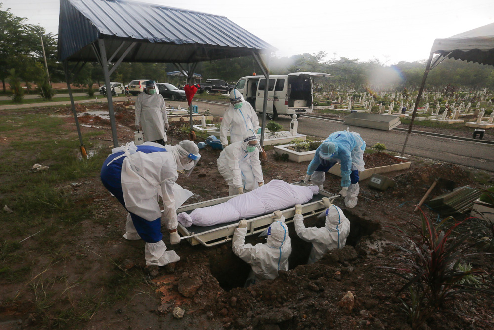 Workers and family members wearing protective suits bury a victim of the Covid-19 disease at a cemetery in Shah Alam May 18, 2021. u00e2u20acu201d Picture by Yusof Mat Isa