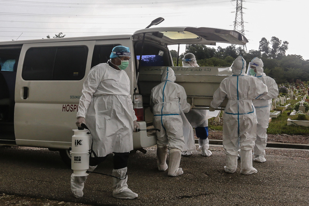 Workers wearing protective suits carry the body of a Covid-19 victim at a cemetery in Shah Alam May 18, 2021. u00e2u20acu201d Picture by Yusof Mat Isa