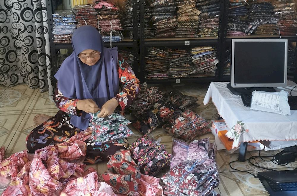 Maishom Abdullah at home sorting clothes to be sent to customers. u00e2u20acu201d Picture via Twitter/AbangUdin