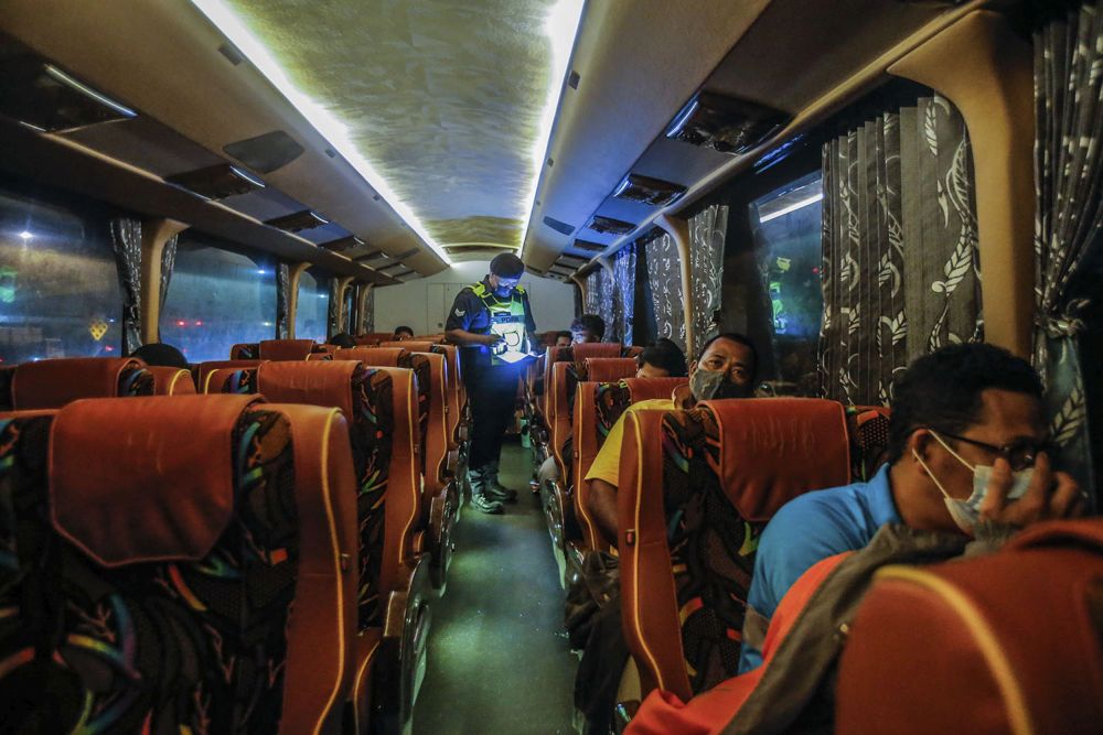 A police personnel checks a buss passenger's travel documents at the Gombak Toll Plaza, Selangor May 5, 2021. u00e2u20acu201d Picture by Hari Anggara