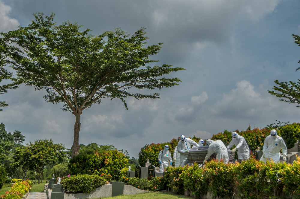 Workers in PPE suits carry the body of a person who died from the coronavirus disease (Covid-19) at a Christian cemetery in Semenyih, Selangor. u00e2u20acu201d Picture by Shafwan Zaidon