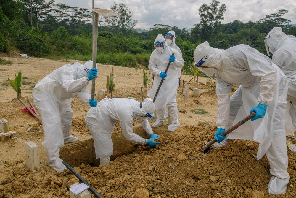 Workers wearing personal protective equipment burying a person who died from Covid-19 at the Muslim cemetery in Gombak June 6, 2021. u00e2u20acu201d Picture by Firdaus Latif