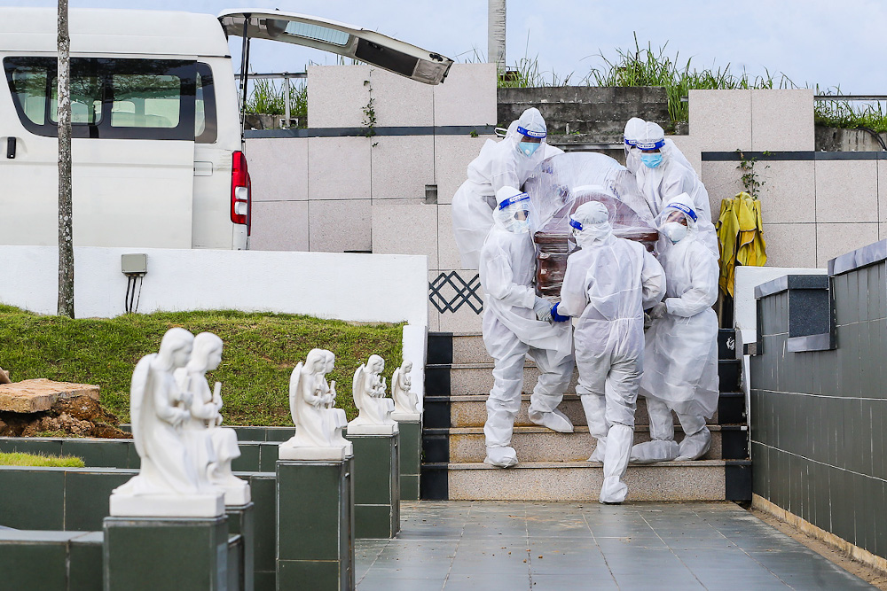 Workers wearing personal protective equipment (PPE) carry a coffin containing a body of a person who died from the Covid-19 disease at the Christian cemetery at Fairy Park in Klang June 6, 2021. u00e2u20acu201d Picture by Yusof Mat Isa