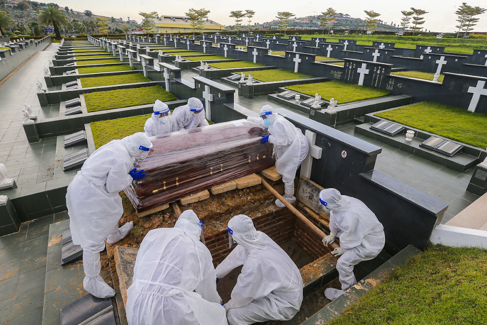 Workers wearing personal protective equipment (PPE) carry a coffin containing a body of a person who died from the Covid-19 disease at the Christian cemetery at Fairy Park in Klang June 6, 2021. u00e2u20acu201d Picture by Yusof Mat Isa