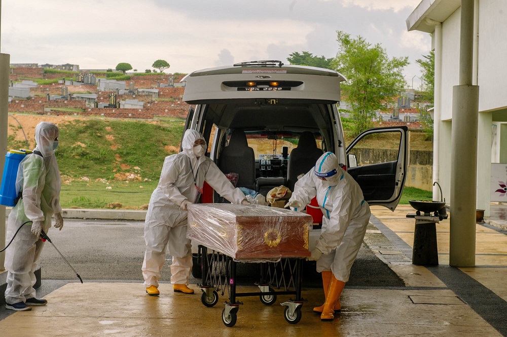 Workers move a casket containing the body of a Covid-19 victim from a hearse into a funeral parlour in Shah Alam June 15, 2021. u00e2u20acu201d Picture By Firdaus Latif