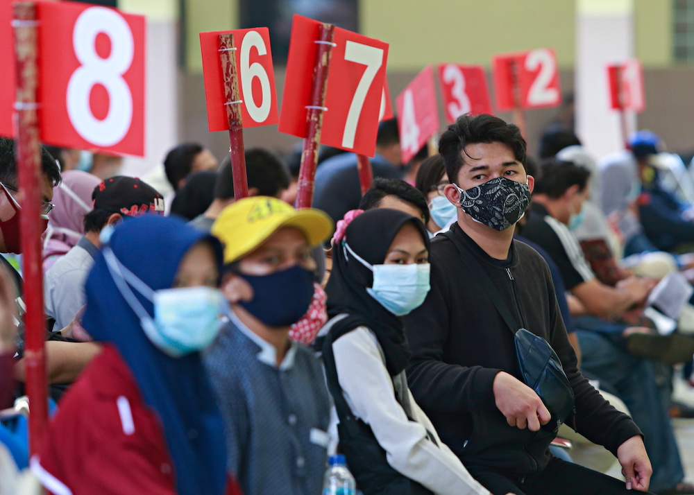 People wearing protective face masks sit before receiving a dose of the coronavirus disease (COVID-19) vaccine during the mass vaccination program at the Tangerang City Government Center, in Tangerang on the outskirts of Jakarta, Indonesia, June 30, 2021.