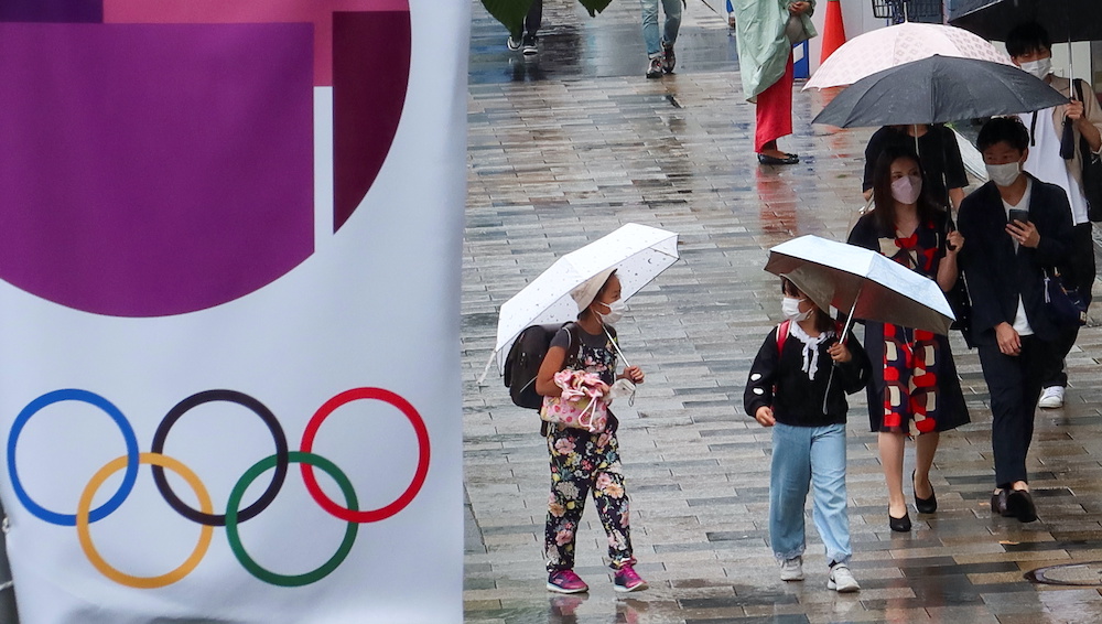 People walk on a street next to an advertisement for Tokyo 2020 Olympic and Paralympic Games, amid the coronavirus disease pandemic, in Tokyo, Japan June 19, 2021. u00e2u20acu201d Reuters picnnnn