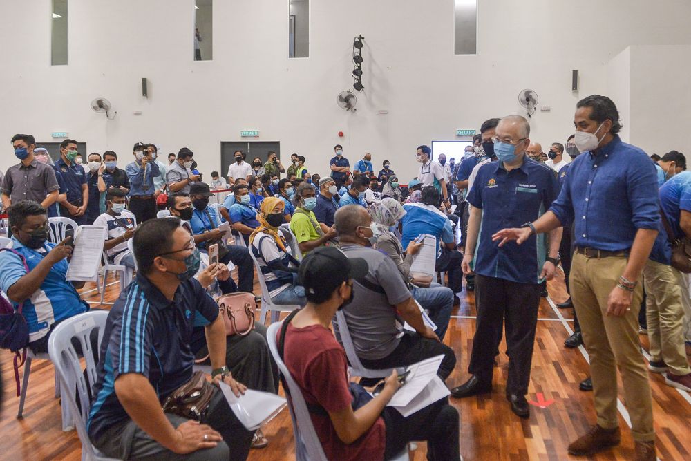 Khairy Jamaluddin (right) and Datuk Seri Wee Ka Siong greet members of the public during a visit to the vaccination centre at the Port Klang Sport Clubu00e2u20acu2122s multipurpose hall June 25, 2021. u00e2u20acu201d Picture by Miera Zulyana