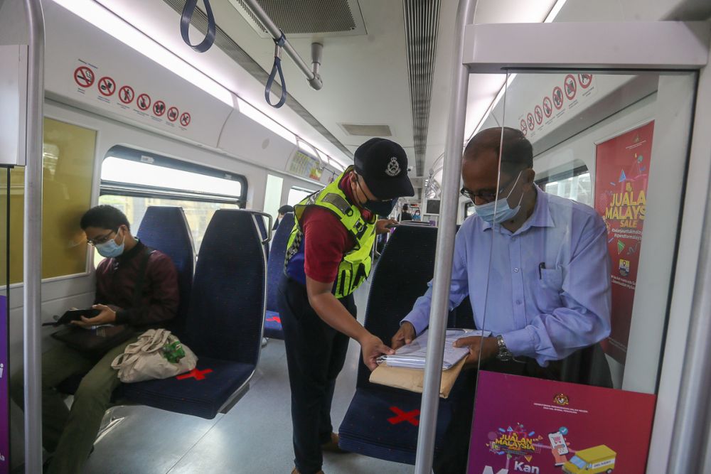 A police personnel conducts checks on KTM passengers in Shah Alam amid the movement control order June 8, 2021. u00e2u20acu201d Picture by Yusof Mat Isa