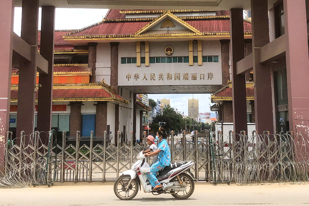 A woman rides a scooter with a child past the China-Myanmar border gate in Muse in Shan state on July 5, 2021, as the Chinese city of Ruili imposed a lockdown and started mass testing. u00e2u20acu201d AFP pic