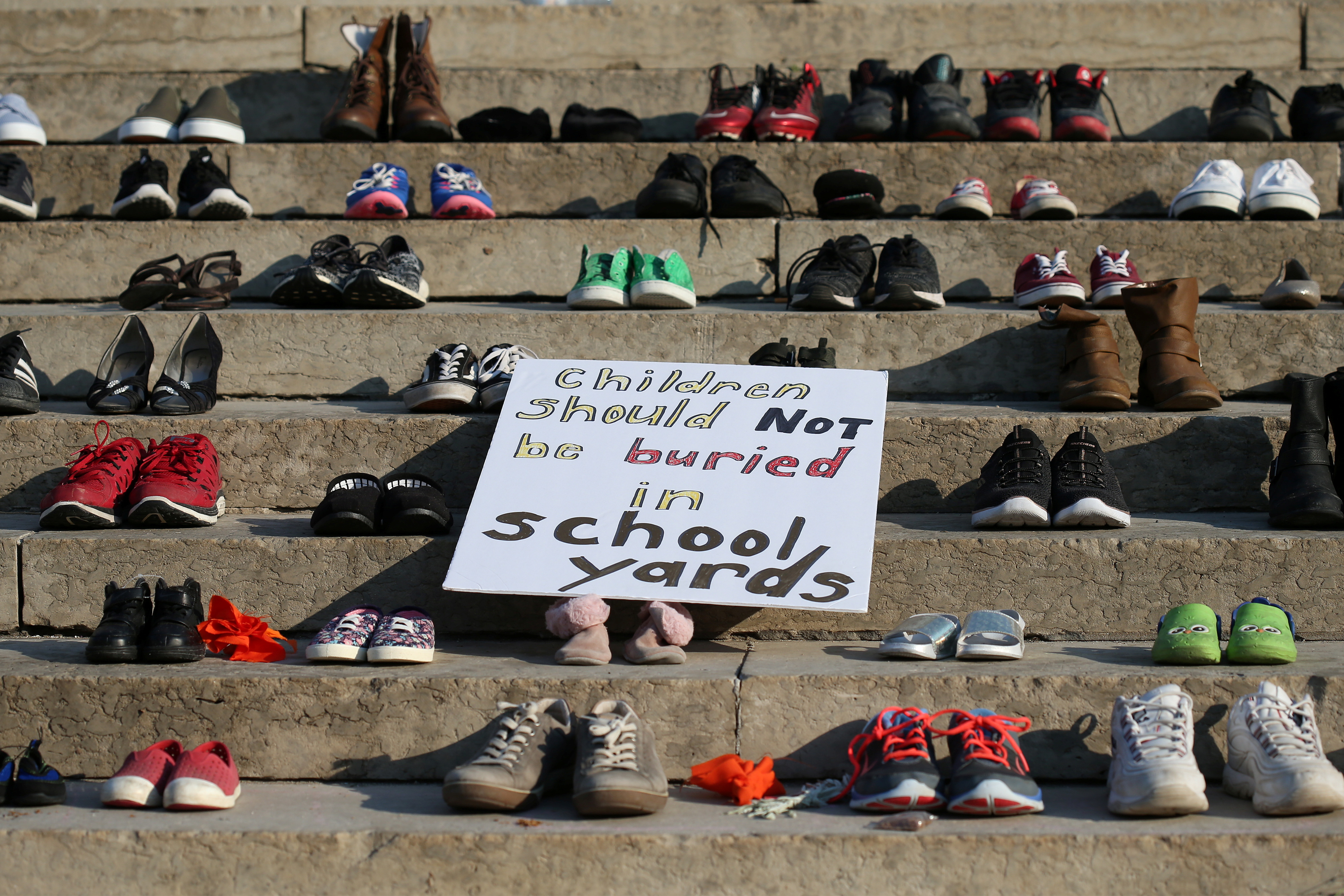 民众制作牌子“孩子不应该被埋在校园里”放在马尼托巴省首府温尼伯议会前面的梯级上。-路透社-