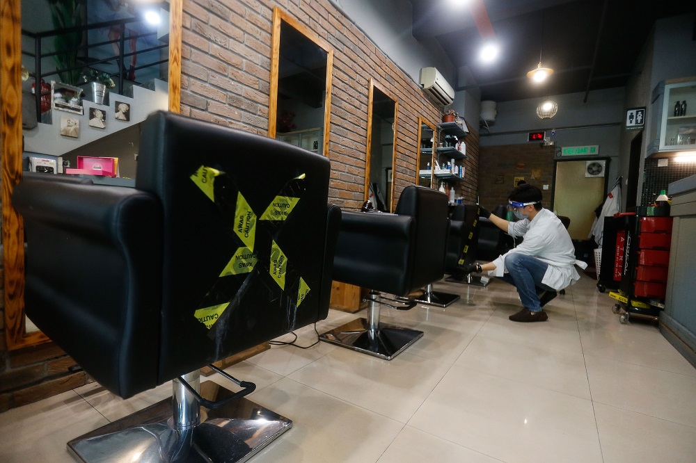 Jonathan Lim marking an X on few of the chairs at his hair salon to ensure physical distancing, at Flair Hair Salon in Bukit Jambul July 7, 2021. u00e2u20acu201d Picture by Sayuti Zainudin