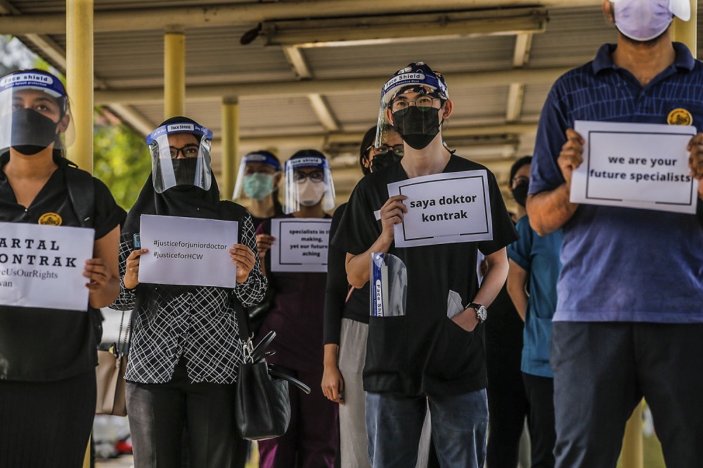 Contract doctors clad in black hold aloft placards demanding equal treatment as they go on strike at the Sungai Buloh Hospital July 26, 2021. u00e2u20acu201d Picture by Hari Anggara 