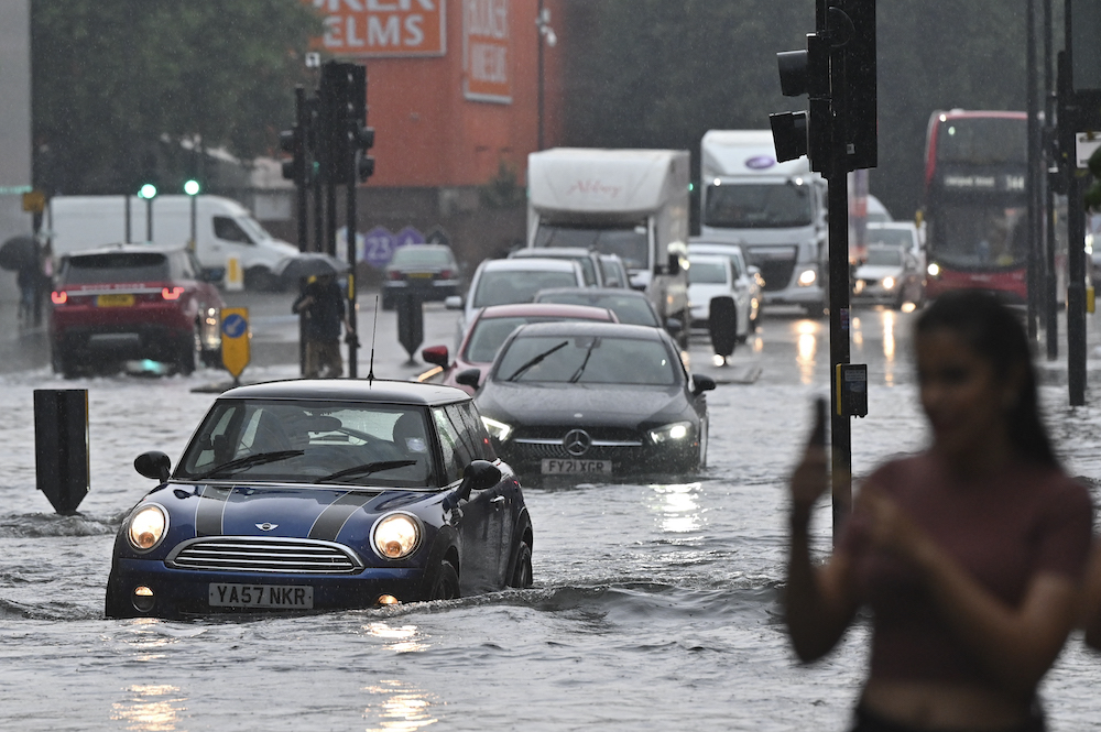 Cars are driven through deep water on a flooded road in The Nine Elms district of London on July 25, 2021 during heavy rain. u00e2u20acu201d AFP pic
