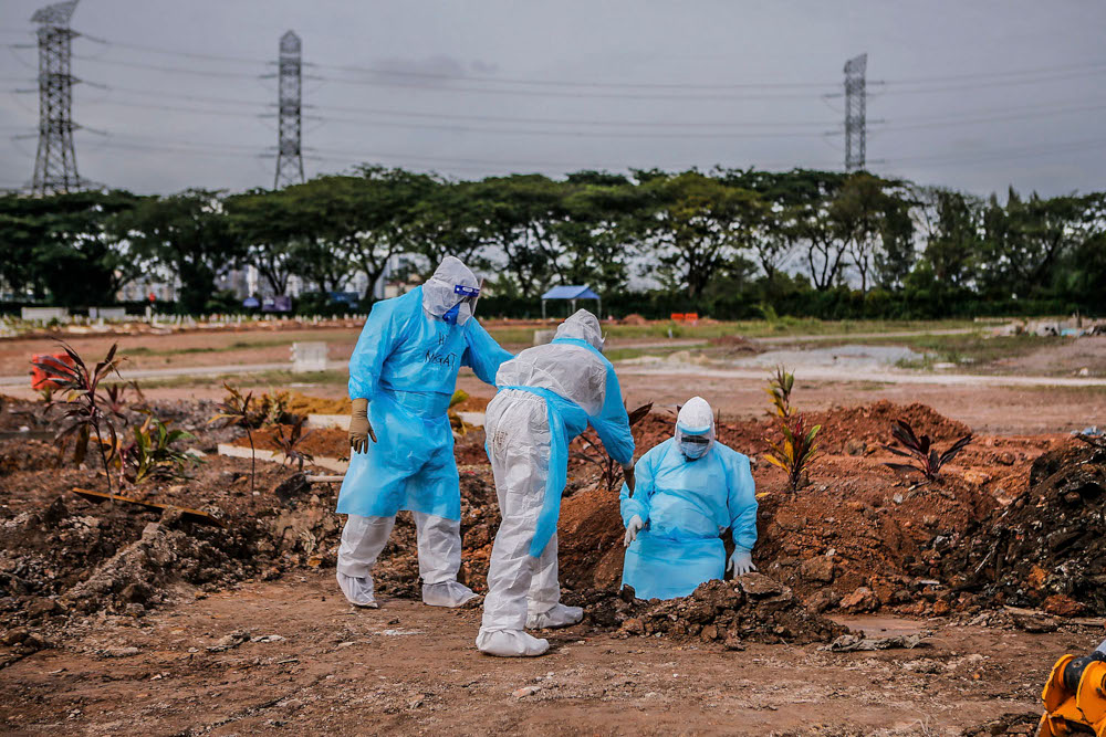 Health workers in personal protective equipment bury the body of a Covid-19 victim at the Muslim cemetery in Section 21, Shah Alam, July 10, 2021. u00e2u20acu2022 Picture by Hari Anggara
