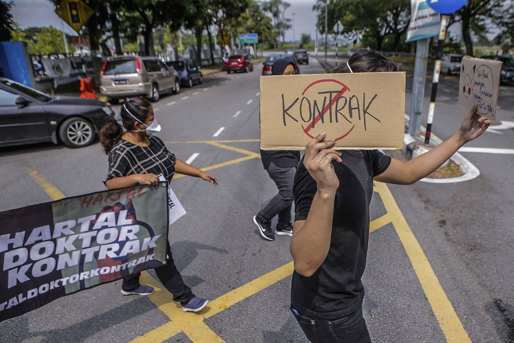 Contract doctors hold aloft placards demanding equal treatment as they go on strike at the Sungai Buloh Hospital July 26, 2021. u00e2u20acu201d Picture by Hari Anggara 