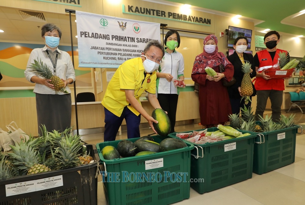 Dr Sim (second left) picks a u00e2u20acu02dcBlack Ladyu00e2u20acu2122 watermelon to be distributed to the frontliners and those in need.  u00e2u20acu201d  Picture by Chimon Upon via Borneo Post Online