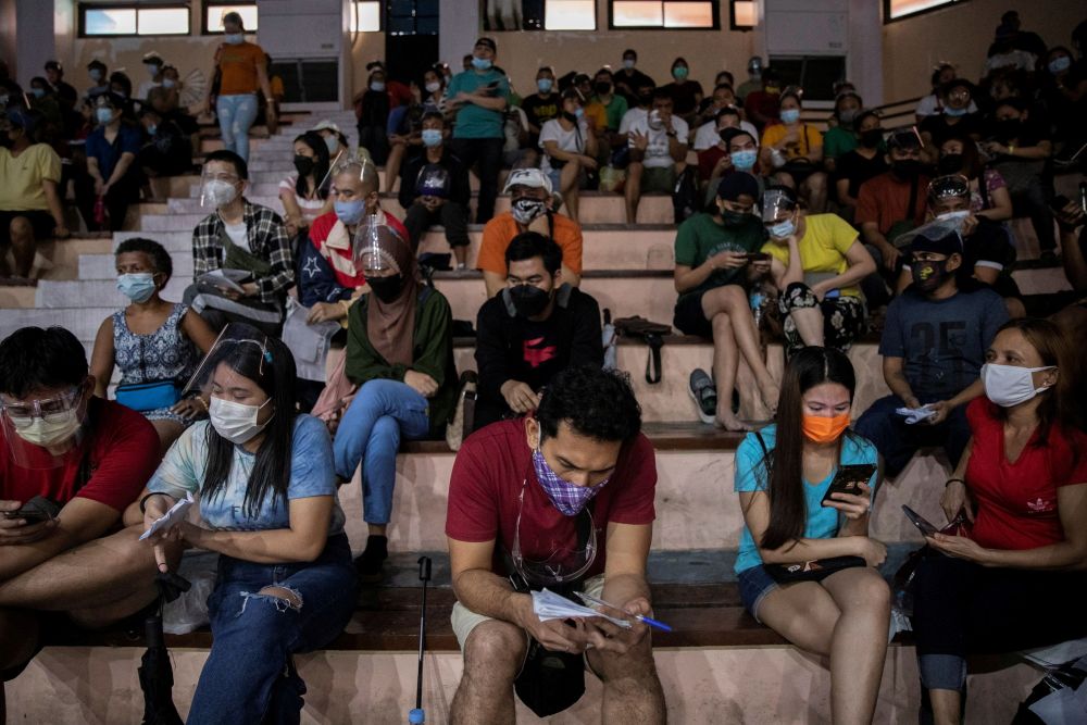 Filipinos use their smartphones while queuing for free vaccination against the coronavirus disease at San Andres Sports Complex in Manila July 21, 2021. u00e2u20acu201d Reuters pic