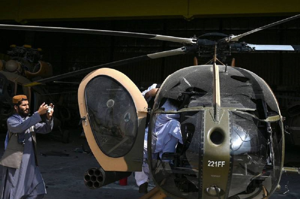 塔利班终于进驻喀布尔机场，一名战士对着美军 MD-530 直升机拍照，画面中可看出这架直升机的座舱玻璃已被砸毁。-法新社-
