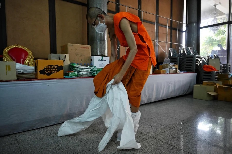 Deputy abbot Mahapromphong from Wat Suthi Wararam Buddhist temple puts on a Personal Protective Equipment (PPE) before going to administer rapid Covid-19 coronavirus tests to residents in the Charoen Krung neighbourhood in Bangkok on July 30, 2021. (Photo