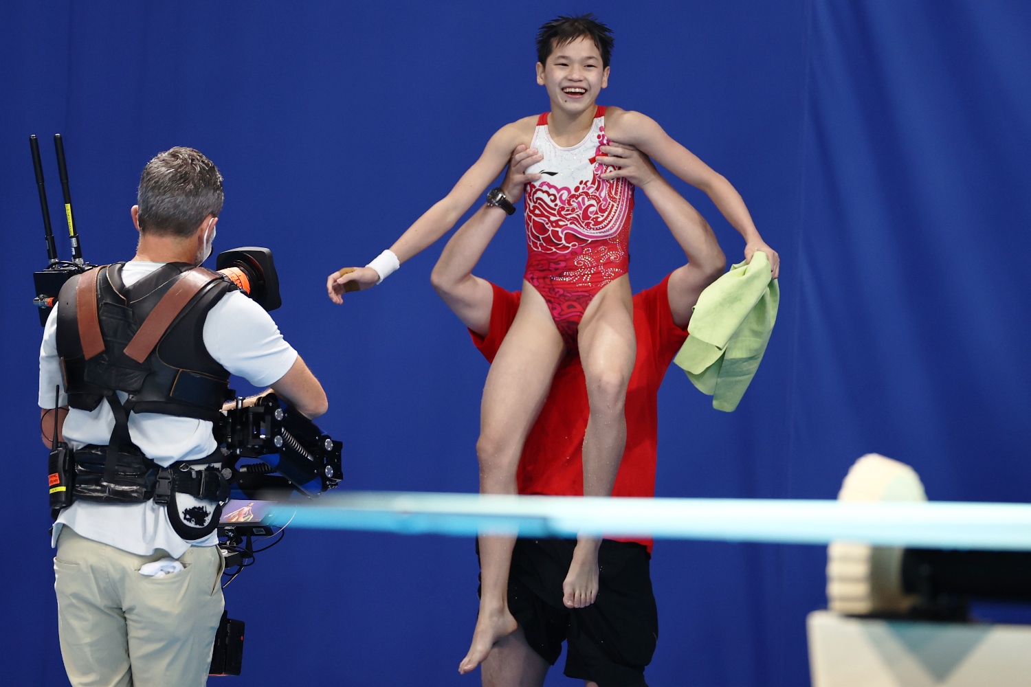 在确认摘金后，全红婵的教练兴奋得把她举起来庆祝。-路透社-