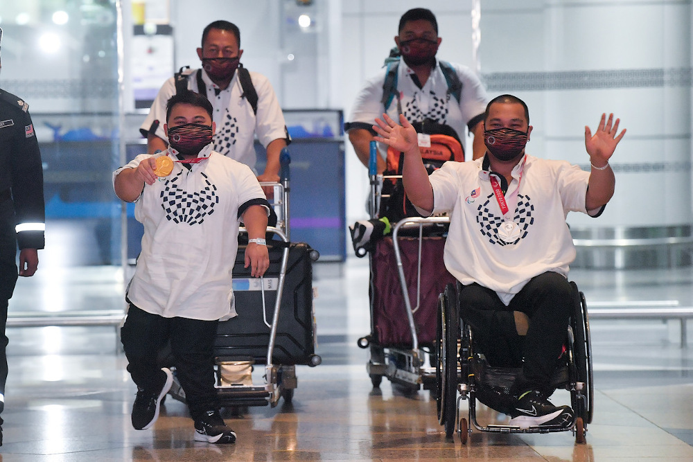 Malaysian powerlifters and Tokyo Paralympic gold medallist Bonnie Bunyau Gustin and silver medallist Jong Yee Khie wave after their arrival at the KL International Airport (KLIA) August 31, 2021. u00e2u20acu201d Bernama pic