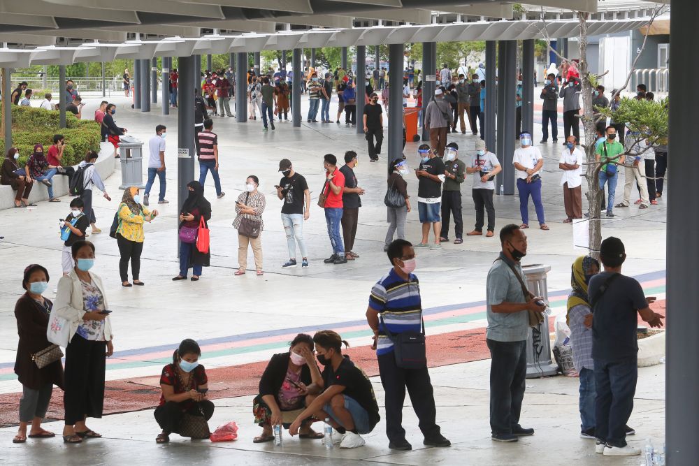 Foreign workers queue as they wait to get their Covid-19 jab at the Bukit Jalil Stadium vaccination centre August 10, 2021. u00e2u20acu2022 Picture by Choo Choy May