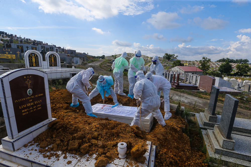 Workers wearing personal protective equipment (PPE) bury a person who died from Covid-19 at the Meru Christian Cemetery in Klang, August 9, 2021. u00e2u20acu2022 Picture by Yusof Mat Isa