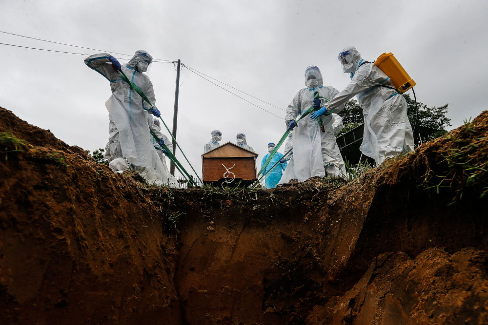 Volunteers prepare to place the body of a Covid-19 victim in the grave for burial at Bagan Ajam Muslim Cemetery, August 24, 2021. u00e2u20acu201d Picture by Sayuti Zainudin