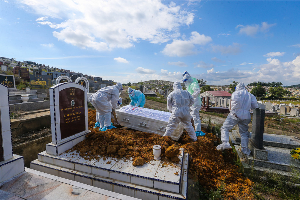 Workers wearing personal protective equipment (PPE) carry a coffin containing the body of a person who died from Covid-19 at the Meru Christian Cemetery in Klang, August 9, 2021. u00e2u20acu2022 Picture by Yusof Mat Isa